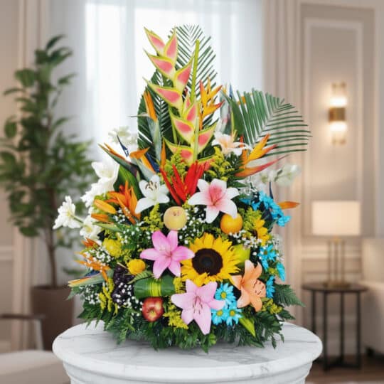 Arreglo floral exótico y vibrante con frutas, lirios, girasoles y aves del paraíso sobre una base de mármol en un entorno ele