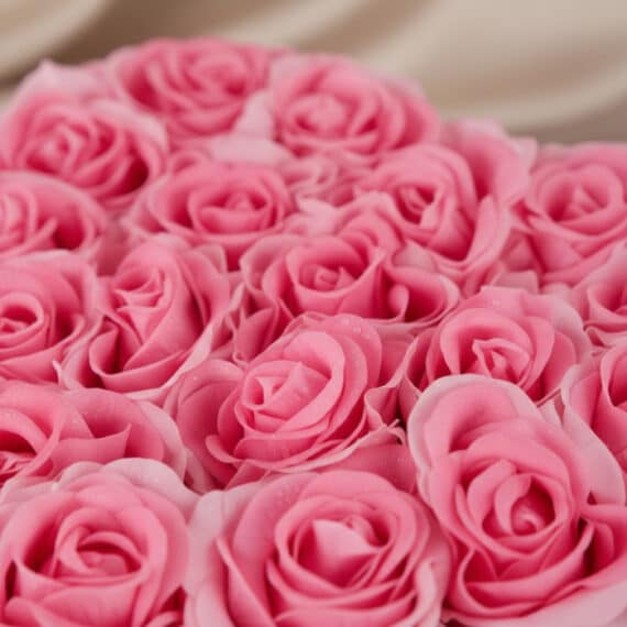 Primer plano extremo de un arreglo floral de rosas rosadas en forma de corazón, con gotas de rocío sutiles y textura hiperrea