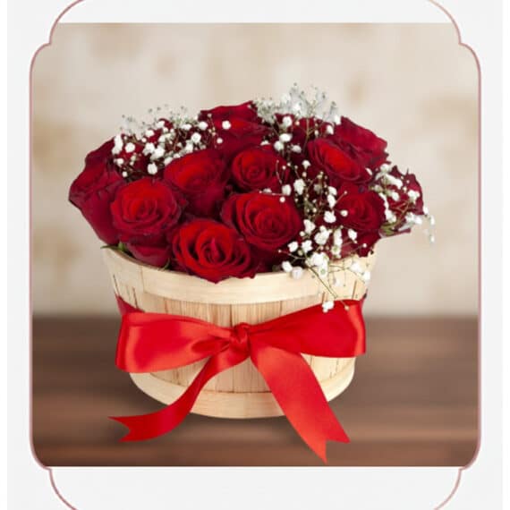 Arreglo Lidia: 15 Rosas Rojas Premium en Balde Rústico Elegante Arreglo floral 'Lidia' con 15 rosas rojas premium en un balde rústico de madera, adornado con un lazo rojo y follaje blanco,