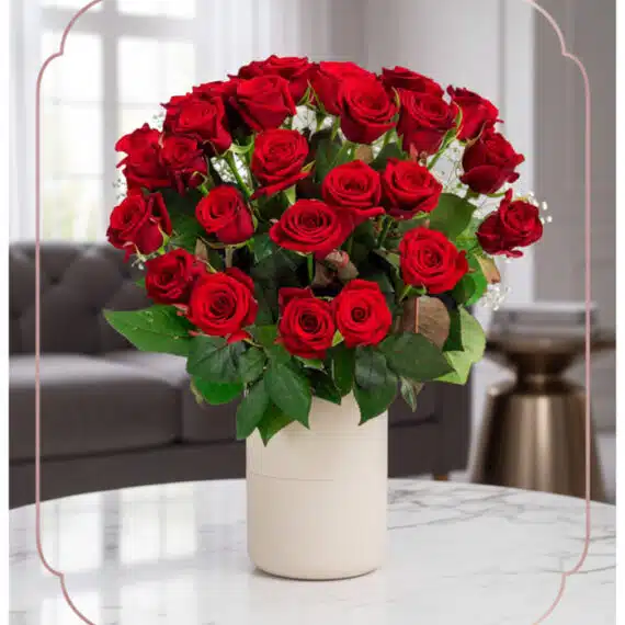 Arreglo Jianna: 25 Rosas Rojas Frescas para Regalo Especial Arreglo floral Jianna con 25 rosas rojas frescas en un elegante jarrón blanco sobre mesa de mármol, fondo difuminado de sala