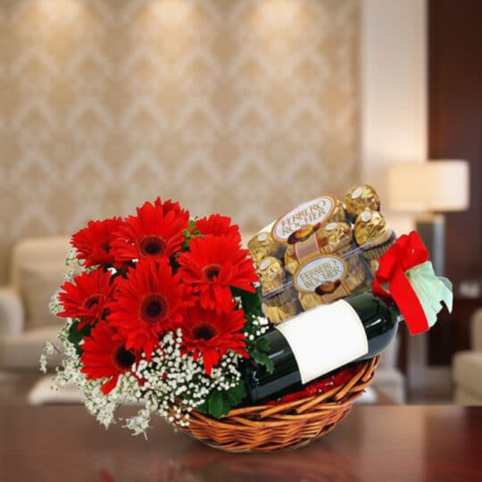 Cesta de regalo ROMA con gerberas rojas, vino tinto y chocolates Ferrero Rocher, ideal para ocasiones especiales.