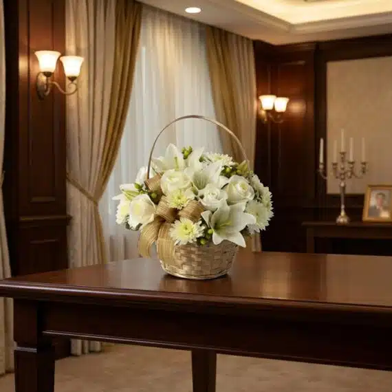 Cubre Caja Fúnebre Elizabeth: Elegancia y Respeto en Cada Flor Cubre Caja Fúnebre Elizabeth, un hermoso arreglo floral en tonos blancos con lirios y rosas, presentado en una cesta de mimbr