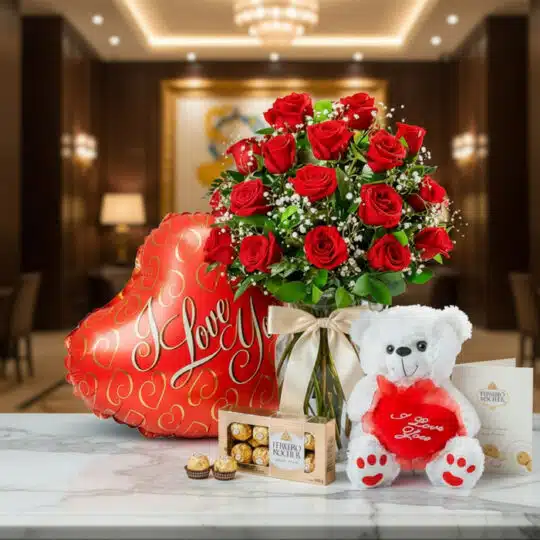 Jarrón Dulce Amor con rosas rojas, un oso de peluche blanco, chocolates Ferrero Rocher y un globo de 'I Love You' sobre mármo