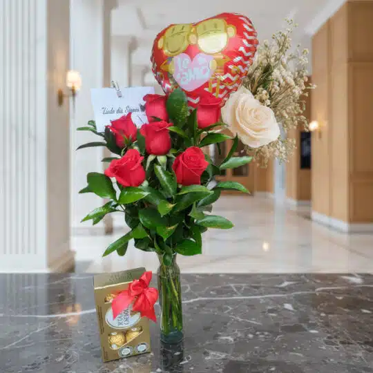 Arreglo floral Solitario con Rosas Me Enamoras, rosas rojas y una rosa blanca, follaje verde, globo de corazón 'Te Amo' y caj